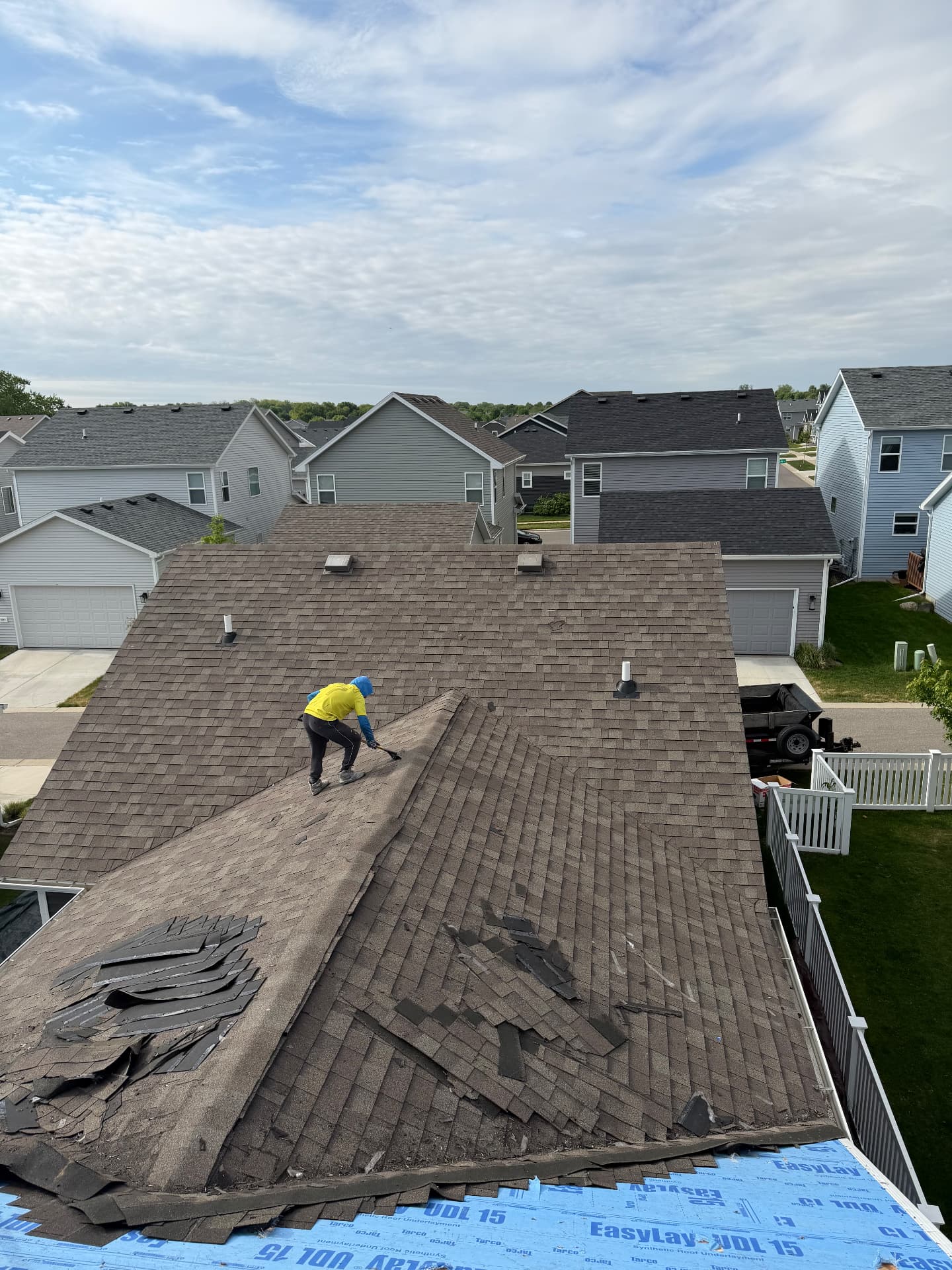 Roofer stripping old shingles on a suburban home