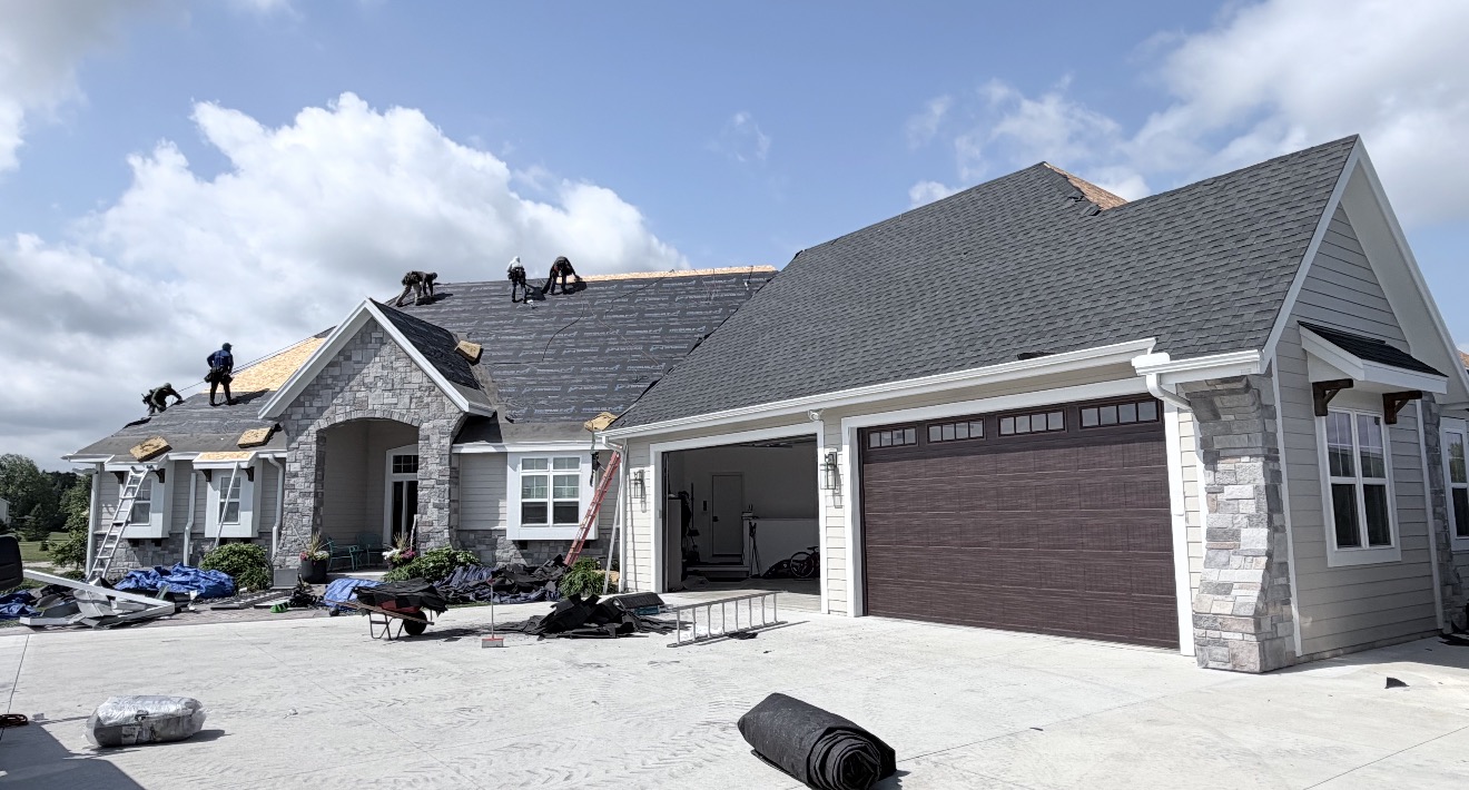 Crew installing a new shingle roof on a large home